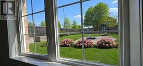 Richmond Hill (Rouge Woods) apartment for rent - A window with a view of a backyard with a bench and flowers.