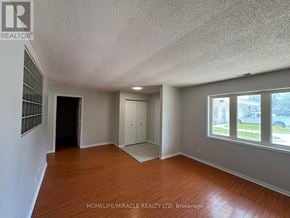Toronto (Kennedy Park) townhouse for rent - A room with wooden floors and white walls, with a window showing a street view.