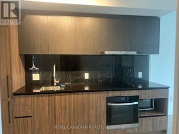 Toronto (York University Heights) condo for rent - A kitchen with wooden cabinets and a black countertop.