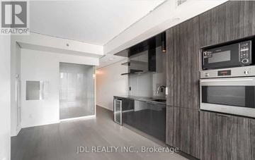Toronto (Bay Street Corridor) condo for rent - A modern kitchen with dark wood cabinets and stainless steel appliances.