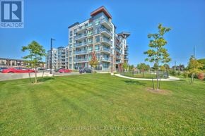 Hamilton (Lakeshore) condo for rent - A large building with a grassy area in front of it.