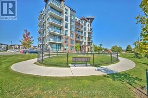 Hamilton (Lakeshore) condo for rent - A large apartment building with a grassy area in front.