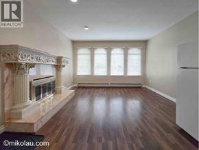 Burnaby apartment for rent - A large, empty room with a fireplace and wood flooring.