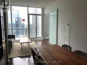 Toronto (Bay Street Corridor) condo for rent - A conference room with a long table and chairs, a couch, and a view of the city through large windows.