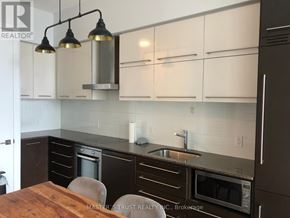 Toronto (Bay Street Corridor) condo for rent - A kitchen with white cabinets and a wooden table.