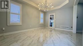 Markham (Berczy) apartment for rent - A spacious room with a chandelier, hardwood floors, and a view of a hallway through a doorway.