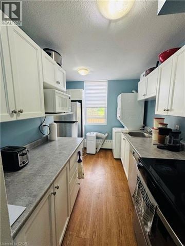 Hamilton condo for rent - A kitchen with white cabinets and a black stove top oven.