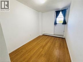 Hamilton condo for rent - A room with wooden flooring and a window with blue curtains.