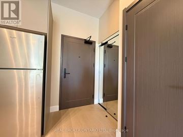 Ottawa condo for rent - A brokerage sign is on the wall above a stainless steel refrigerator in a modern kitchen.