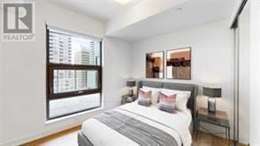 Toronto (Bay Street Corridor) condo for rent - A bedroom with a large bed and a window overlooking a cityscape.