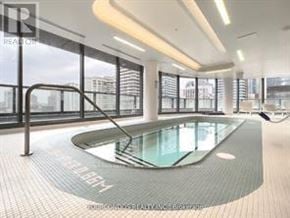 Toronto (Bay Street Corridor) condo for rent - A modern indoor swimming pool with a glass bottom and a metal railing.