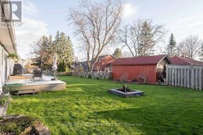 Whitchurch-Stouffville apartment for rent - A backyard with a red house and a green lawn.