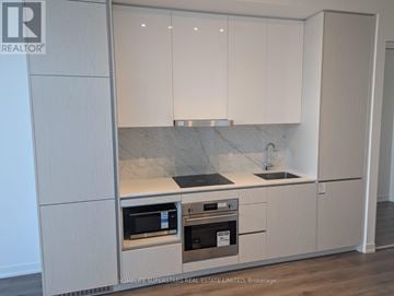 Vaughan (Vaughan Corporate Centre) condo for rent - A kitchen with white cabinets and a marble countertop.