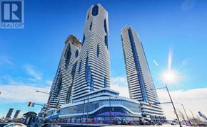 Vaughan (Vaughan Corporate Centre) condo for rent - A modern building with a glass facade stands tall against a clear sky.