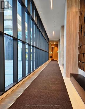 Vaughan (Vaughan Corporate Centre) condo for rent - A long hallway with a carpeted floor and a wall of windows on one side.