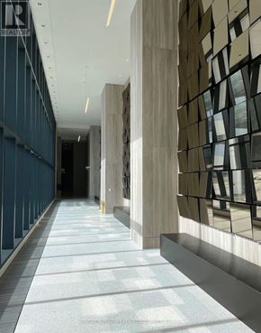 Vaughan (Vaughan Corporate Centre) condo for rent - A long hallway with a tiled floor and a wall with a window.