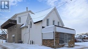 Barrie (City Centre) apartment for rent - A white house with a sign that says Bay Street Group Inc. Brokerage.