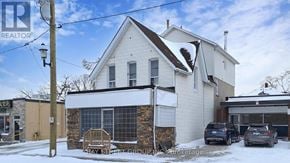 Barrie (City Centre) apartment for rent - A white house with a brown roof and a sign that says "Bay Shore Group Inc. Brokerage".