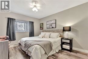 Hamilton condo for rent - A bedroom with a bed, nightstand, and a window with curtains.