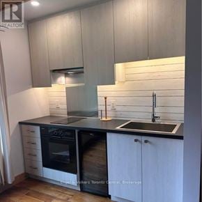 Blue Mountains apartment for rent - A modern kitchen with white cabinets and black countertops.