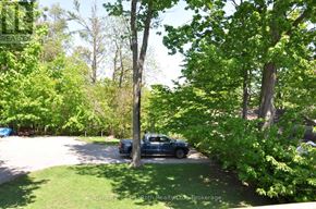 Orillia apartment for rent - A blue truck is parked in a driveway surrounded by green trees.
