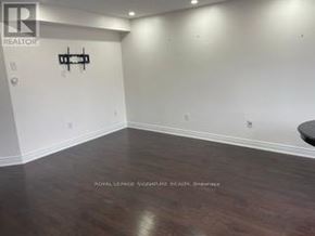 Whitby (Pringle Creek) townhouse for rent - A room with wooden flooring and a white wall with a black sign.