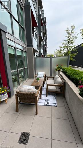 Burlington condo for rent - A patio with a table and chairs is in front of a building.