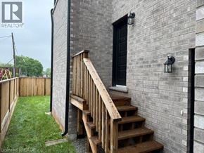 Hamilton apartment for rent - A wooden staircase leads up to a black door on a grey brick building.