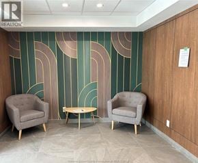 Windsor condo for rent - Two grey chairs and a table are in front of a green and gold wall.