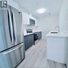 Windsor condo for rent - A modern kitchen with a refrigerator, microwave, and oven.