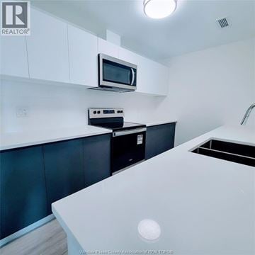 Windsor condo for rent - A kitchen with a microwave and oven mounted on the wall.