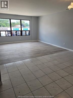 Windsor apartment for rent - A large empty room with a tiled floor and a view of a street through the windows.