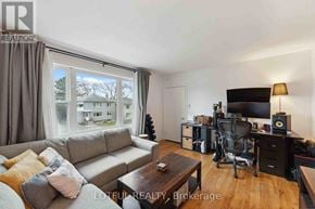 Ottawa duplex for rent - A living room with a grey couch, a coffee table, a television, and a desk with a chair.