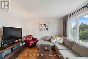 Ottawa duplex for rent - A living room with a grey couch, a red chair, and a flat screen TV.