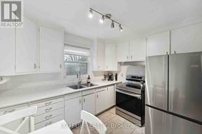 Ottawa duplex for rent - A white kitchen with a refrigerator, sink, and oven.