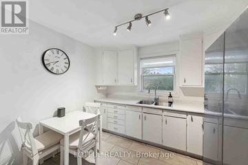 Ottawa duplex for rent - A white kitchen with a table and chairs and a clock on the wall.
