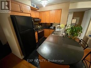Toronto (Bayview Village) condo for rent - A kitchen with a black fridge and wooden cabinets.