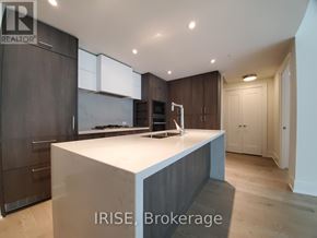Toronto (Waterfront Communities) condo for rent - A modern kitchen with dark wood cabinets and a white island.
