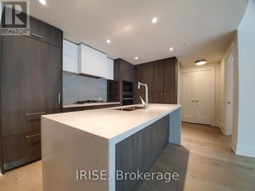 Toronto (Waterfront Communities) condo for rent - A modern kitchen with dark wood cabinets and a white island.