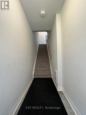Oshawa (Samac) apartment for rent - A hallway with a staircase leading to a door at the end.