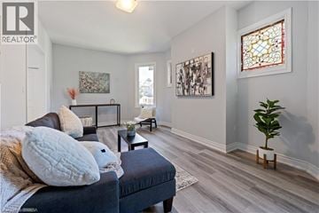 Brantford apartment for rent - A living room with a dark blue couch and a small plant on the right side.