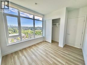 Burnaby apartment for rent - A room with a large window overlooking a cityscape.