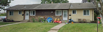 North Saint Paul apartment for rent - A house with a white door and windows is surrounded by a lawn and a sidewalk.