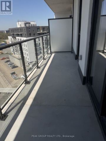Brantford condo for rent - A balcony with a metal railing and a view of a parking lot and buildings.
