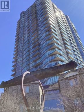 Toronto (High Park-Swansea) condo for rent - A tall building with many windows and a sculpture in front of it.