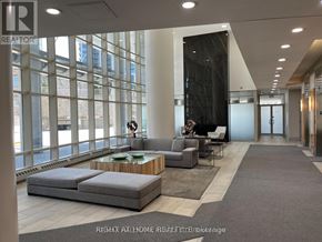 Toronto (High Park-Swansea) condo for rent - A woman is standing in a spacious living room with a large window and a fireplace.