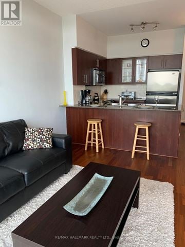 Toronto (High Park-Swansea) condo for rent - A black couch sits in a living room with a wooden coffee table in front of it.