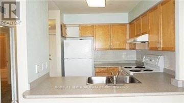 Toronto (Willowdale East) condo for rent - A kitchen with wooden cabinets and a white fridge.