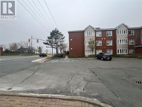 St John's house for rent - A black car is parked in a parking lot in front of a brick apartment building.