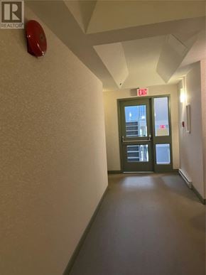 St John's house for rent - A hallway with a green door and an exit sign above it.